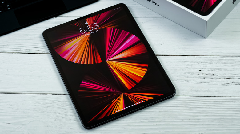 Apple iPad Pro lying on a white wooden surface with the screen turned on.