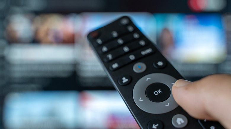 media remote control with person's finger visible pressing a button on the side