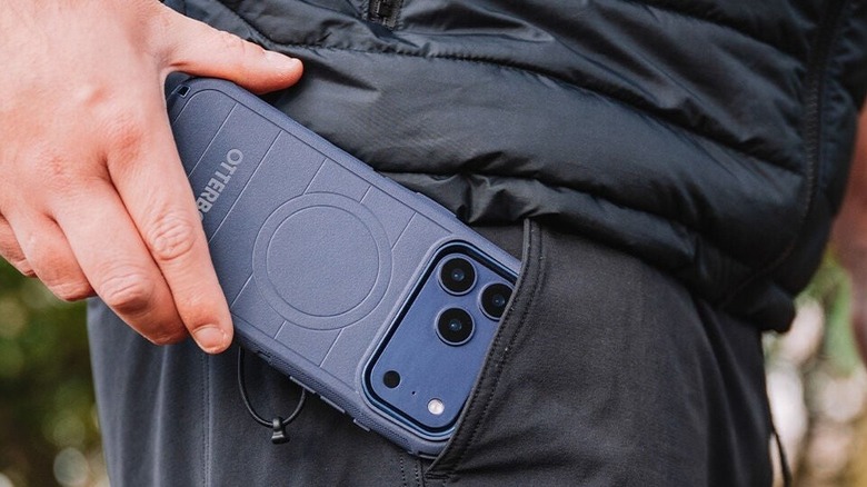 A person sliding an iPhone sporting the Otterbox Defender Pro case into their pocket