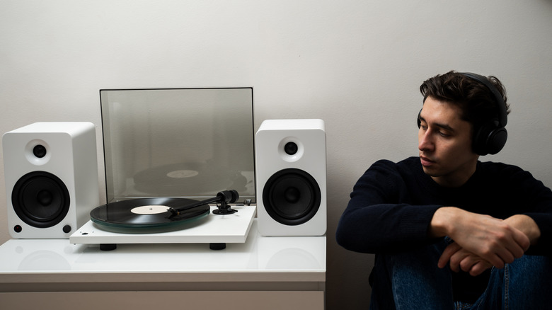 A person listening to music from a record player on white speakers