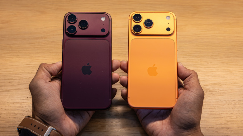 person's hands holding two iphones