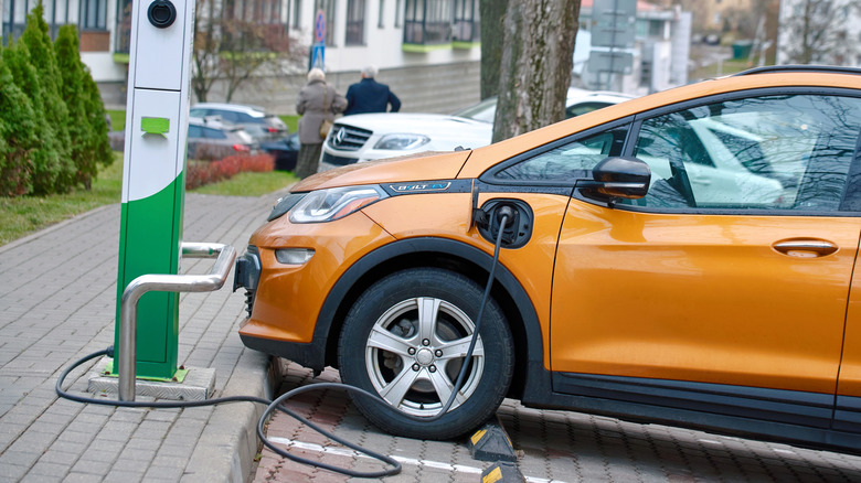 Orange Chevy Bolt plugged into public charger.