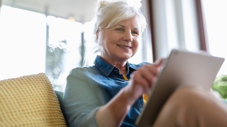 woman using digital tablet while sitting on sofa at home