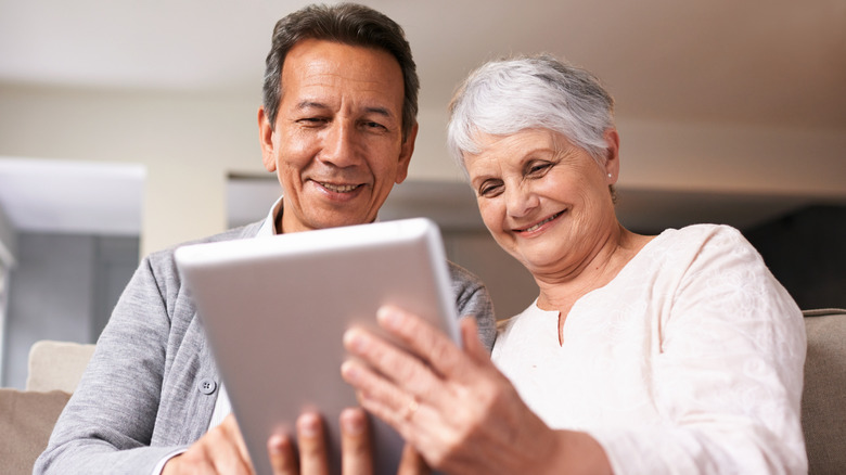 A senior couple using a digital at home.