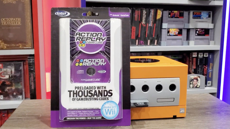 A packaged Action Replay accessory propped up against a GameCube console