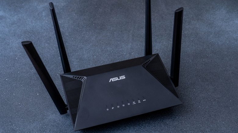 A black ASUS router with four antennas on a stone tabletop