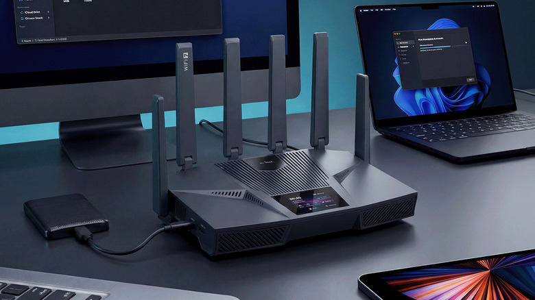The GL.iNet Flint 4 Wi-Fi 7 router on a desk surrounded by devices