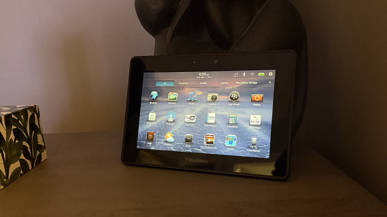 A BlackBerry Playbook leaning against a statue on a table.