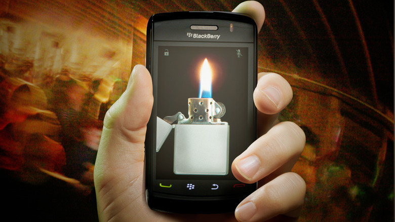 A hand holding a BlackBerry storm with the image of a lighter on it.