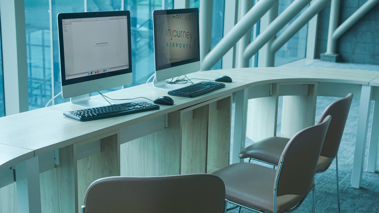 Computer workstations with keyboard and monitors on a table with chairs