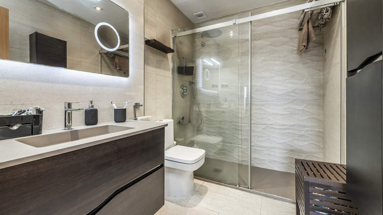 A household bathroom with closed shower stall, sink counter, toilet, and a closed crate
