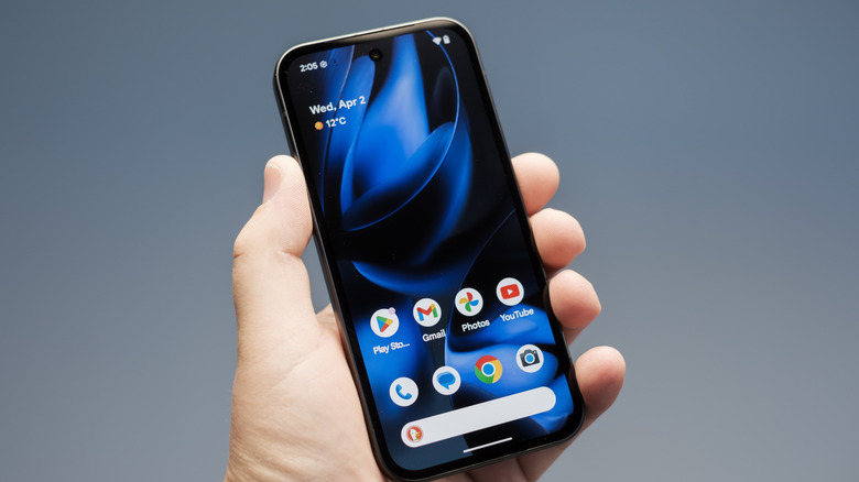 hand holding pixel 9a smartphone on blue gradient background