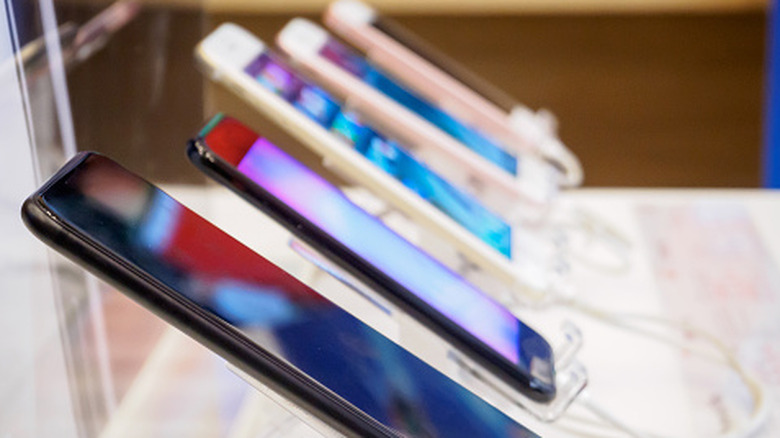multiple smartphones lined up in a store, viewed from the side