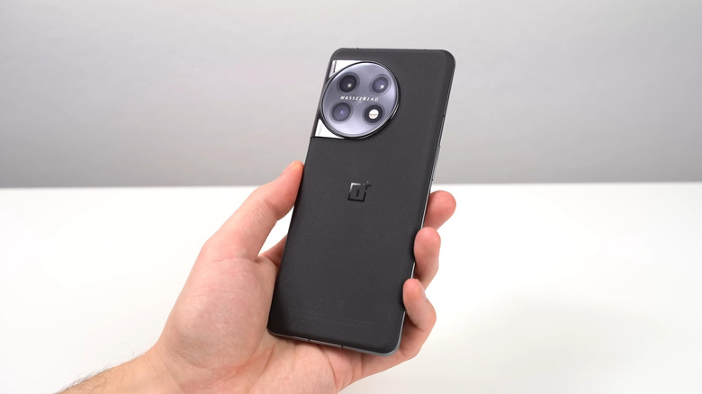 a person holding up a OnePlus 11 showing the back logo