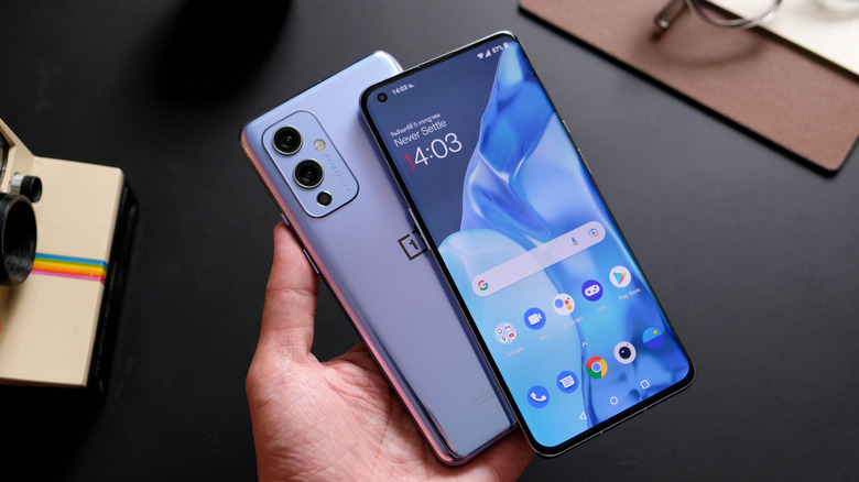 A person holding a OnePlus 9 and OnePlus 9 Pro