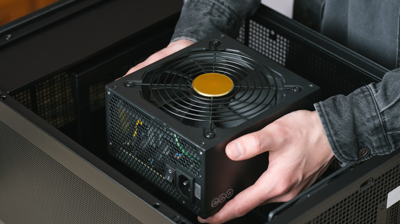A person installing a PSU in a PC case
