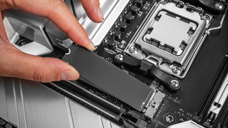 A person installing SSD storage stick in a motherboard