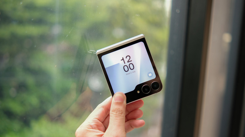 Someone holding the corner of a Galaxy Z Fold 7 FE against a window