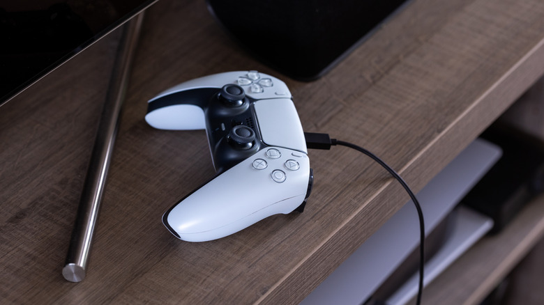 a DualSense PlayStation 5 controller with a USB-C wire connected