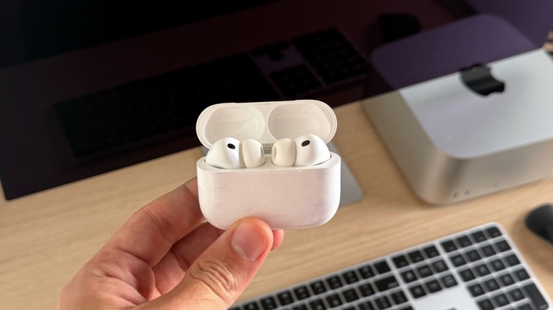 AirPods Pro 3 in their charging case with a Mac Studio and Studio Display behind