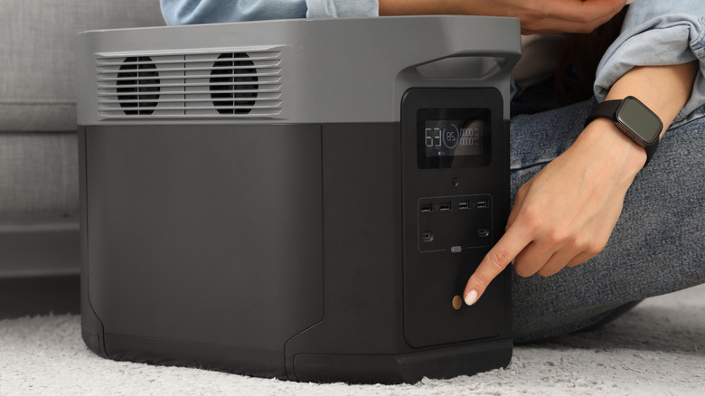 A person turning on a portable power station in their home