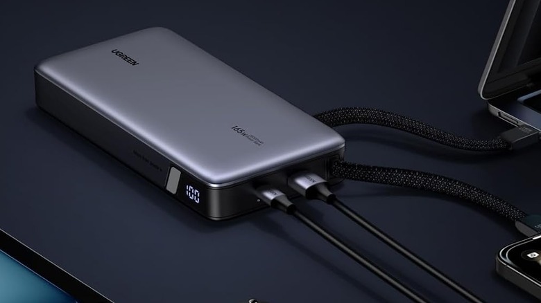 Ugreen Nexode 25,000 mAh Power Bank on a dark blue surface connected to multiple devices