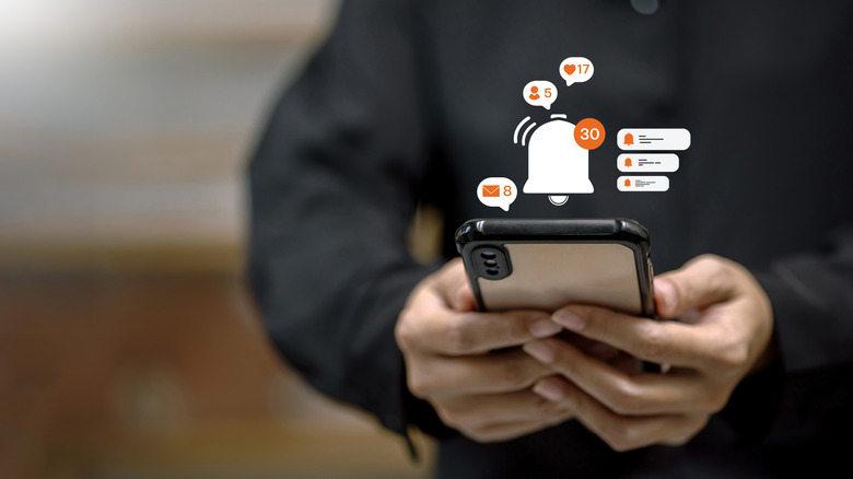 concept of man holding smartphone with notifications icon showing above it.