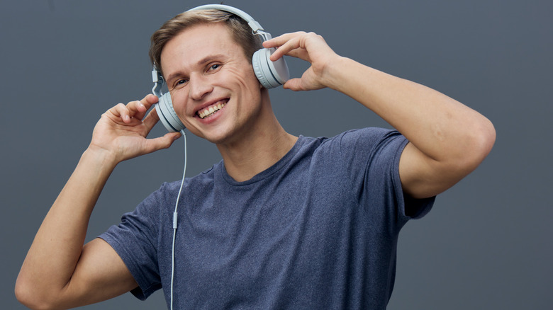 A man wearing wired headphones while smiling at the camera
