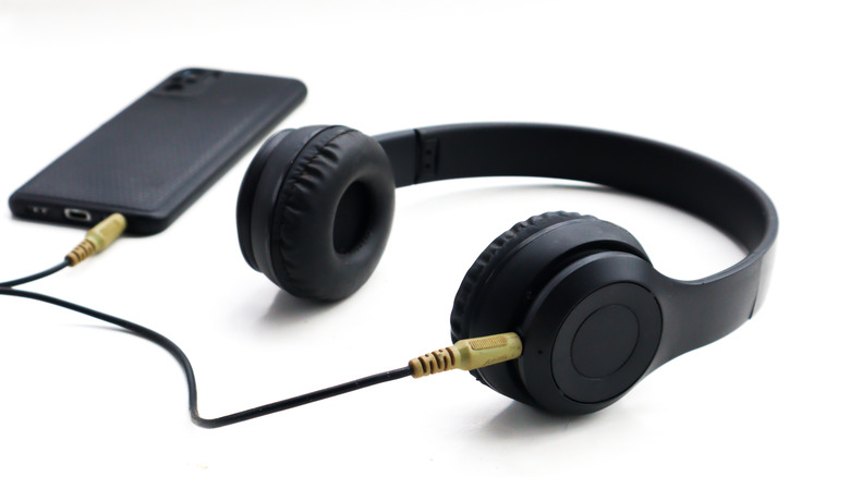 Black wired headphones plugged into a phone