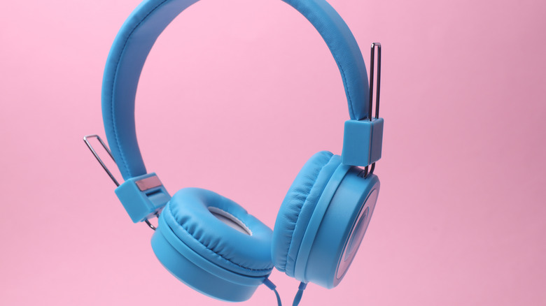 Blue wired headphones against a pink background
