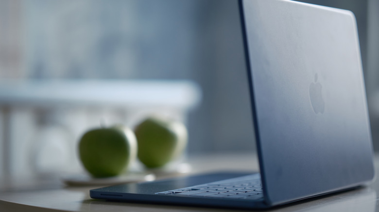 A modern lifestyle photo featuring a sleek blue laptop on a kitchen table in a stylish contemporary home interior