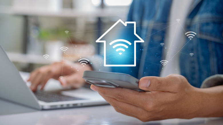 Someone holding smartphone with home Wi-Fi icons visible in the air conceptually.