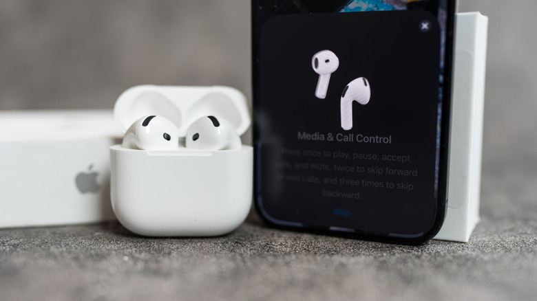 close-up on AirPods 4 in case next to iPhone