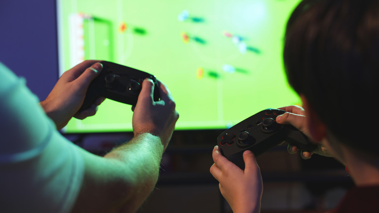 Adult and child holding game controllers and playing home video games