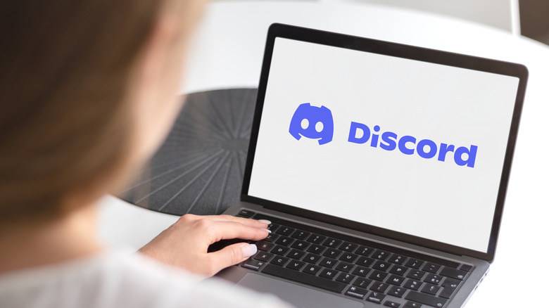 Discord logo displayed on a laptop with a person sitting in front of it