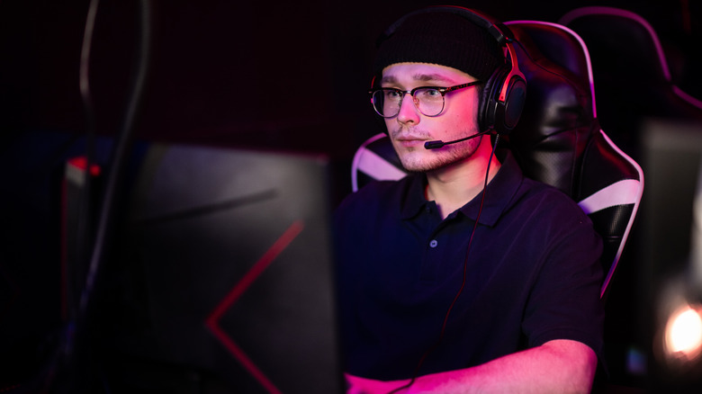 a cyberathlete playing in a hosted esports tournament while wearing a headset and gaming on a pc