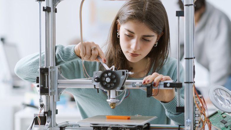 Person using a tool to adjust a 3D printer rail