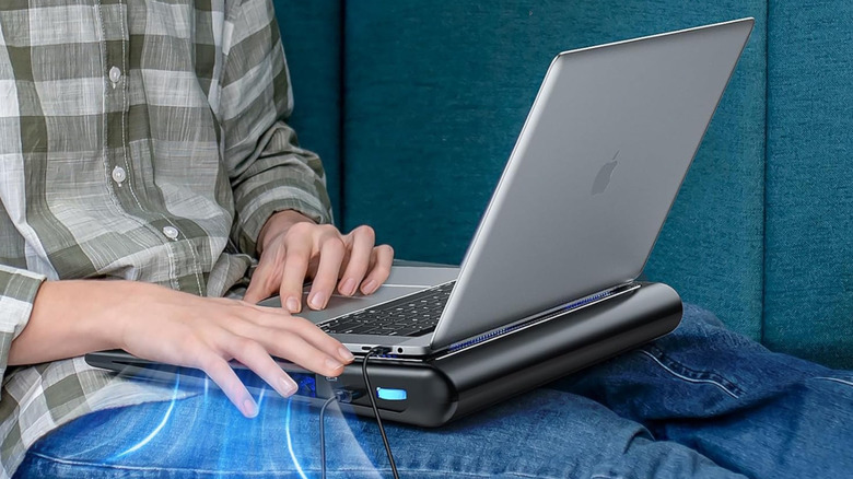 A person using a laptop that's on a laptop cooling pad.