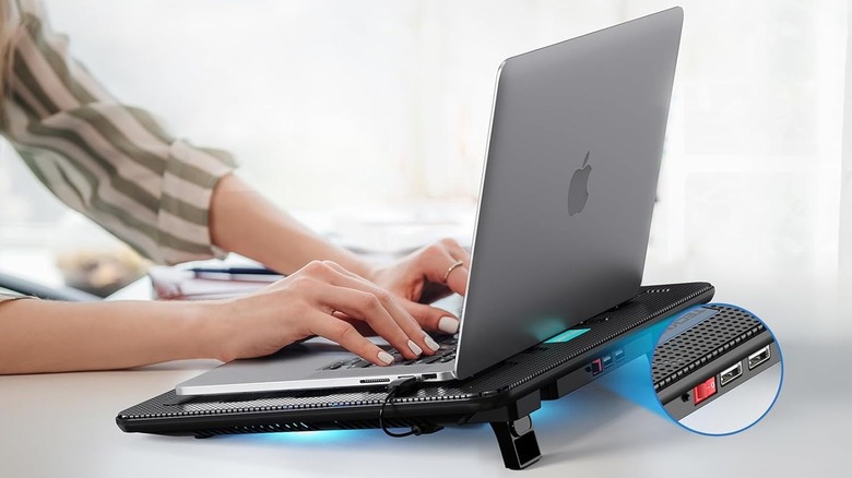 A person using a laptop on a cooling pad. There's a circular, picture-in-picture closeup of the pad's USB ports.