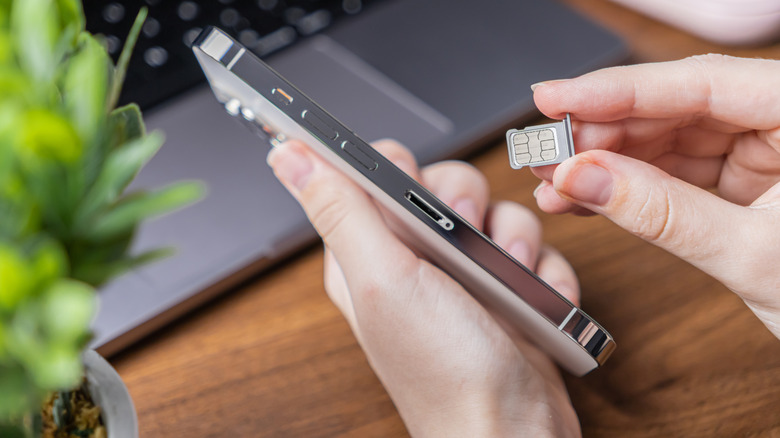 A person inserting a SIM card into an iPhone