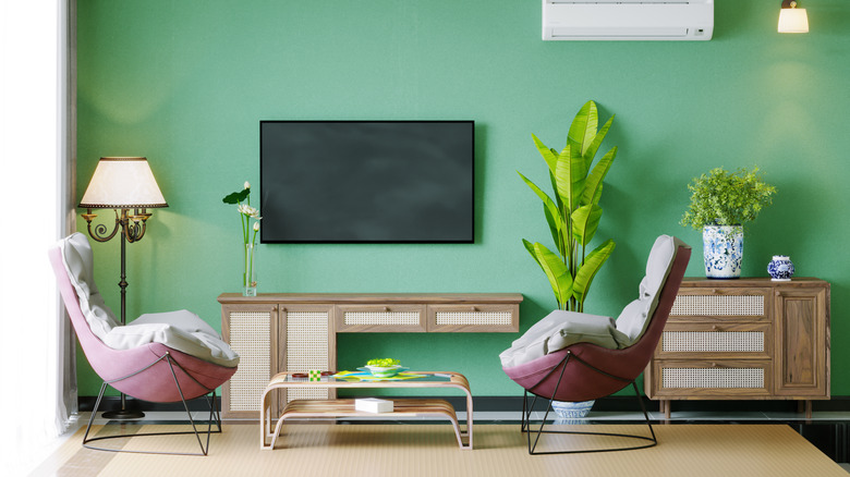 A modern living room with a wall-mounted flat-screen TV centered on a green accent wall.