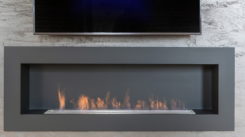 A wall-mounted flat-screen TV positioned above a modern recessed fireplace.