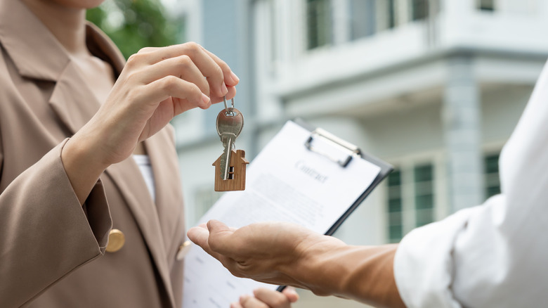 A close-up of a person handing over house keys during a property transaction.