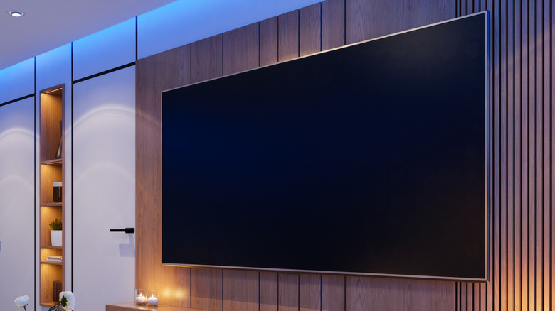 A large flat-screen TV mounted on a modern wood-paneled wall in a contemporary living room.