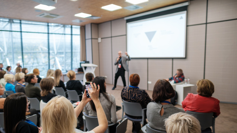 An audience attending a conference presentation in a modern meeting room.