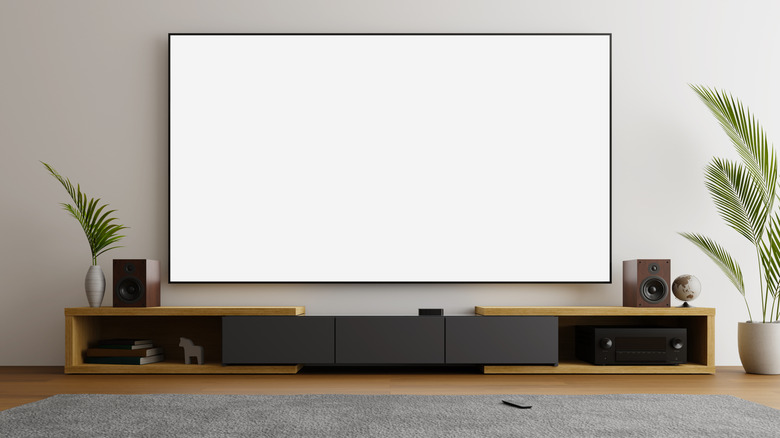 A home theater setup with a projector screen, speakers, and a media console.