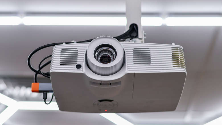 A ceiling-mounted projector installed with a blurred room in the background.
