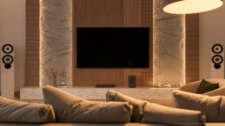 A modern living room with a wall-mounted TV and floor-standing speakers.