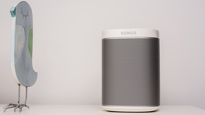 A Sonos speaker placed next to a bird statuette.