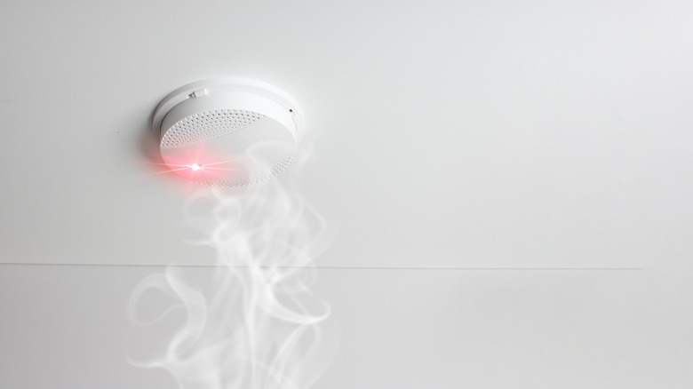 A smoke alarm pinging as smoke rises up to it.